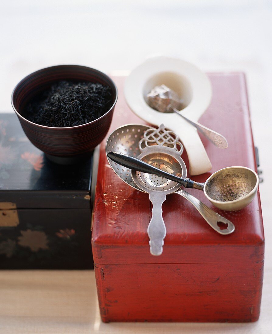 Verschiedene Teesiebe, schwarze Teeblätter, Holzschachteln