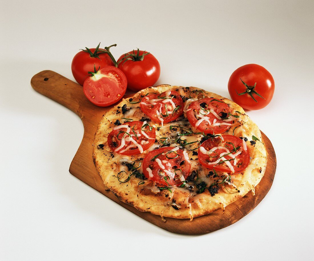 Pizza mit Tomaten auf Holzbrett