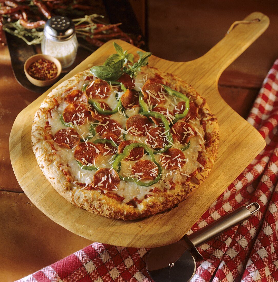 Pizza mit Peperoni-Wurst, Paprika und Käse auf Holzbrett