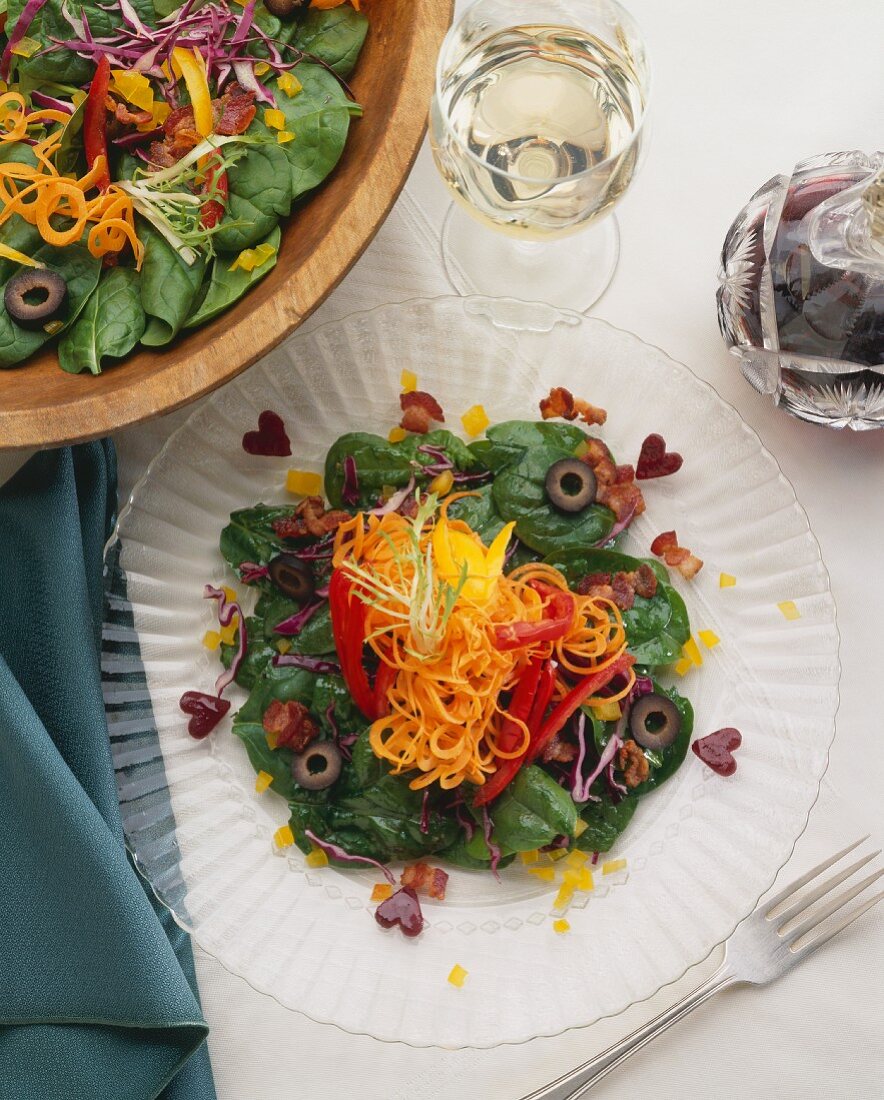 Spinach Salad on a Glass Plate and in Serving Bowl; From Above; Glass of White Wine