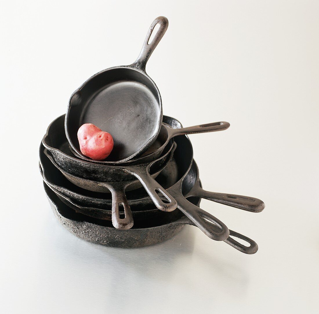 Stack of Cast Iron Skillets with a Red Potato
