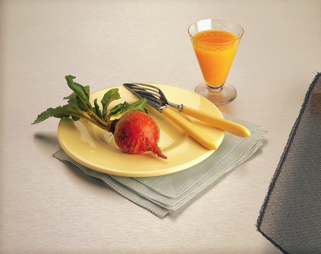Golden Beet on Plate with Fork and Knife; Glass of Carrot Juice