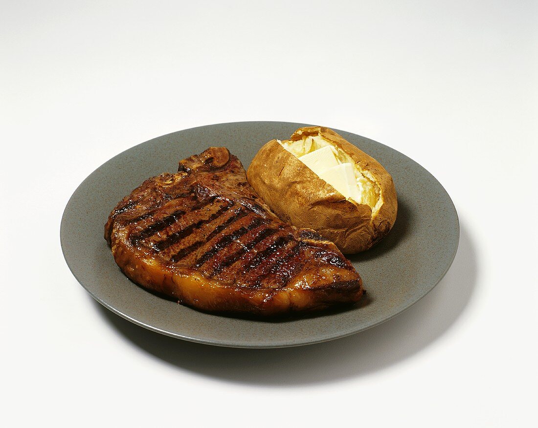 Gegrilltes T-Bone-Steak mit Ofenkartoffel auf Teller
