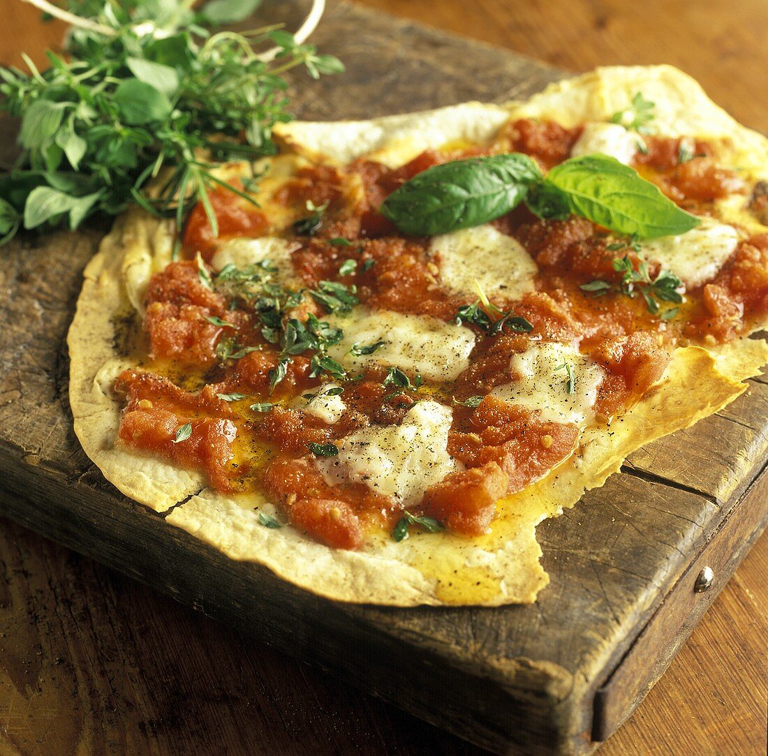 Pizza mit Tomaten, Mozzarella und frischen Kräutern