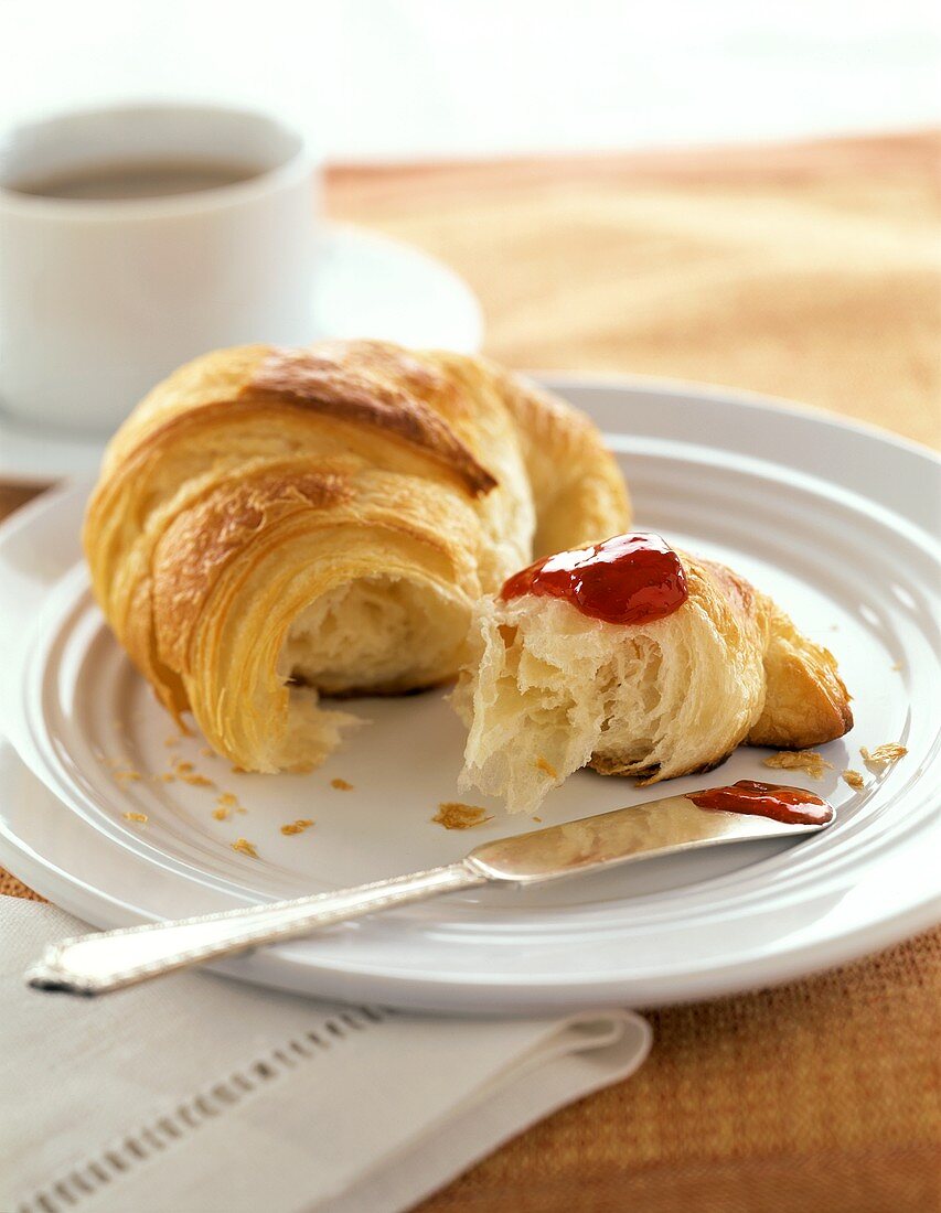 Croissant mit Erdbeermarmelade und eine Tasse Kaffee