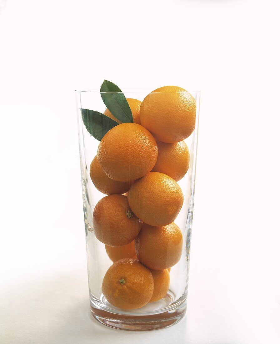 Orangen mit Blättern in einem Glas