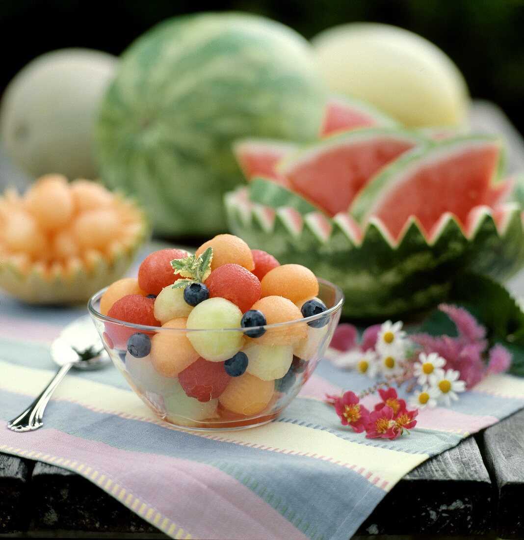 Bunte Melonenkugeln mit Heidelbeeren in Glassschale