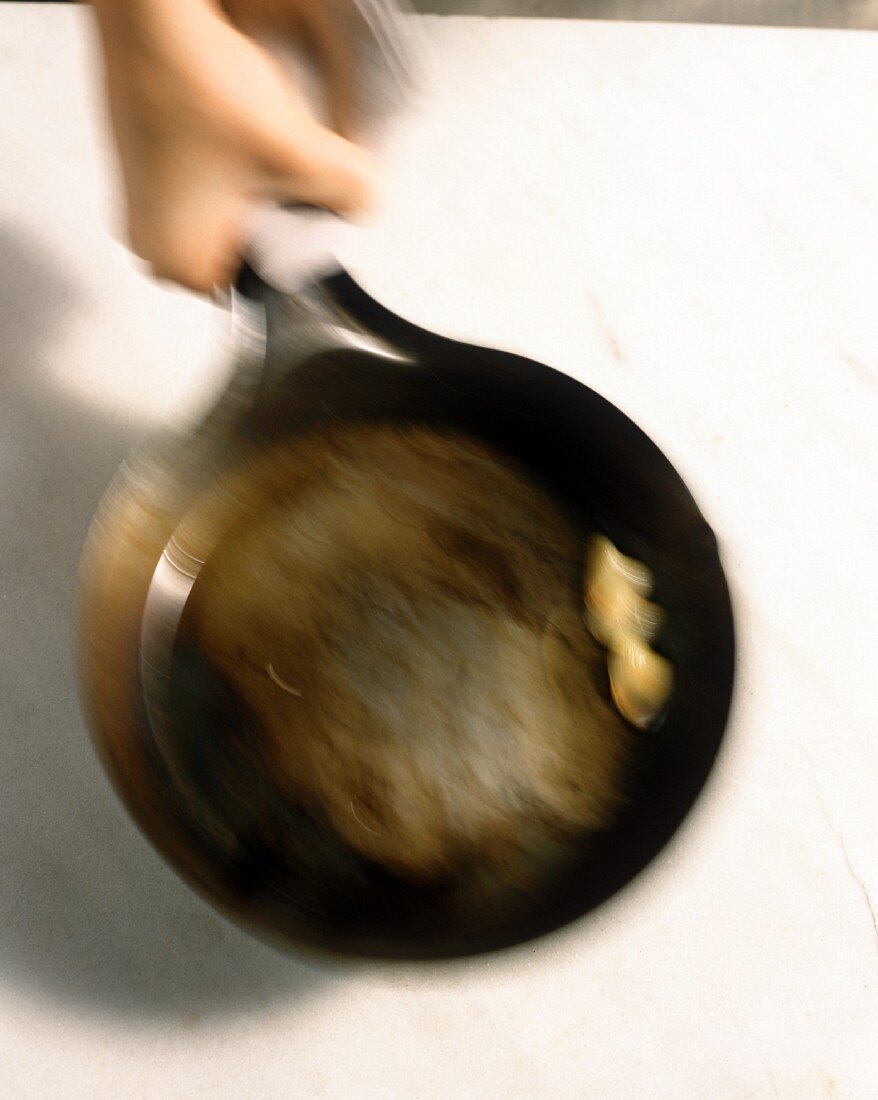 Tossing garlic cloves in pan