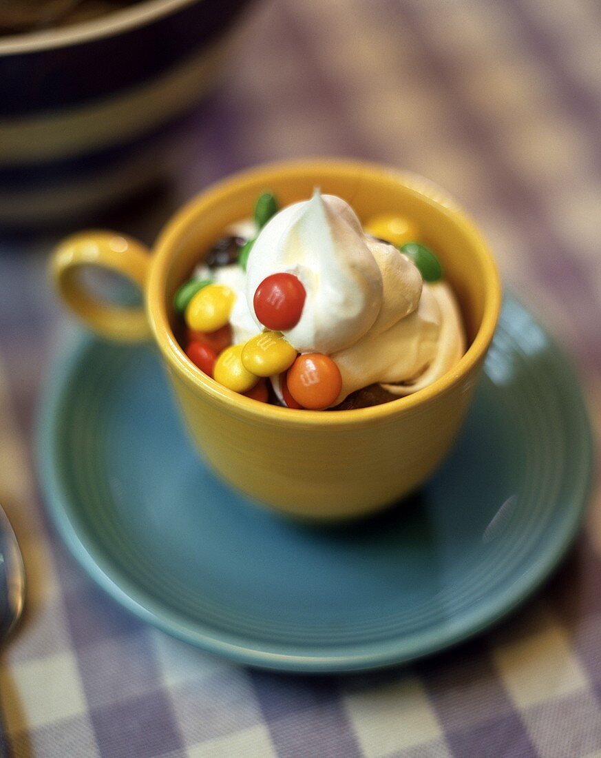 Schokoladencreme mit Sahne und bunten Schokolinsen in Tasse