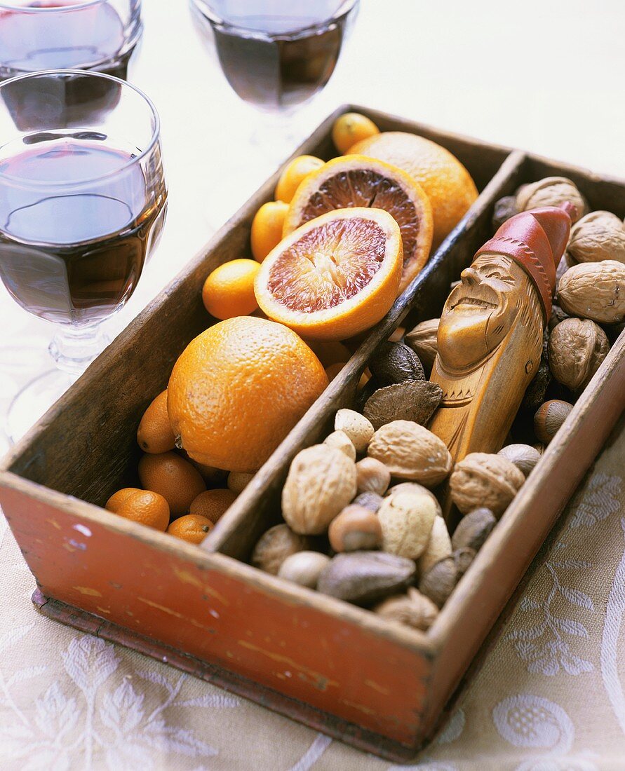 Punch glasses beside box with oranges, nuts & nutcracker