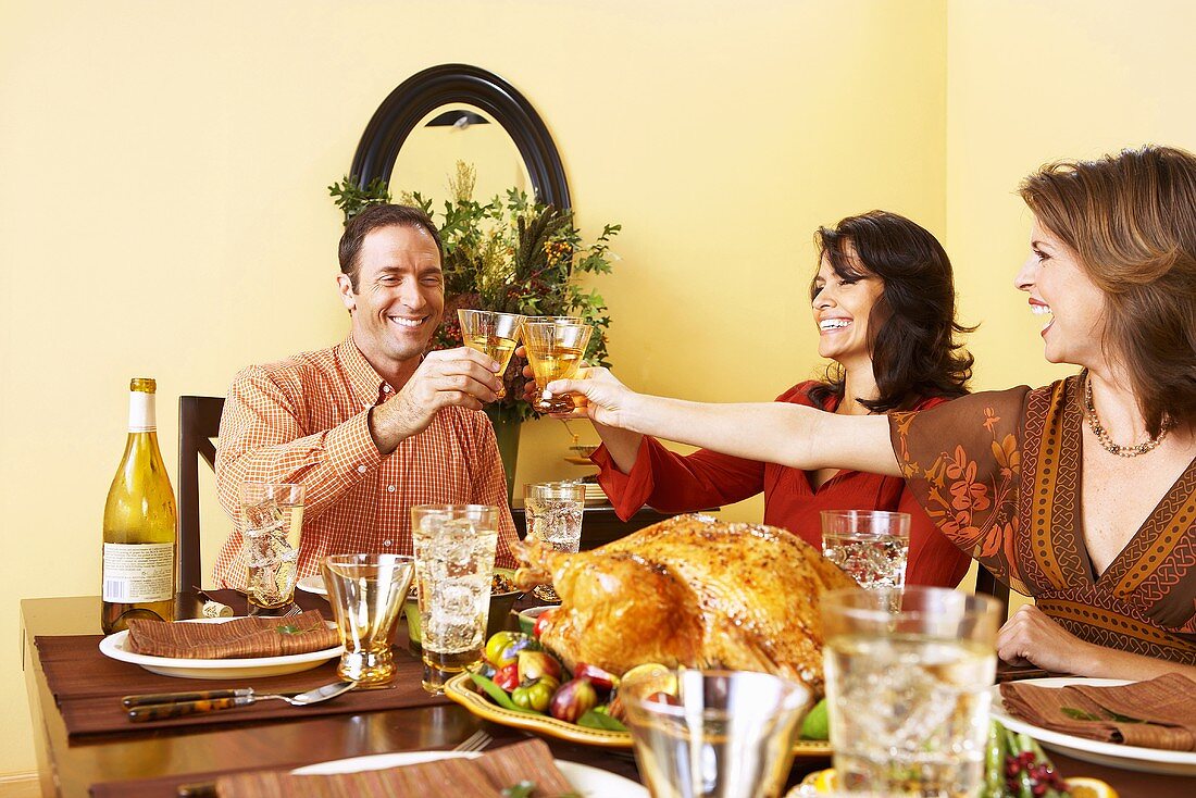 Leute stossen mit Weingläsern an beim Thanksgiving-Essen