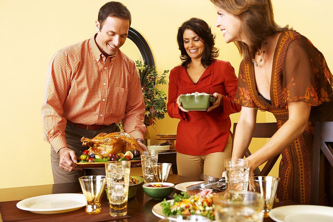 Leute decken Tisch mit Turkey und Beilagen zu Thanksgiving