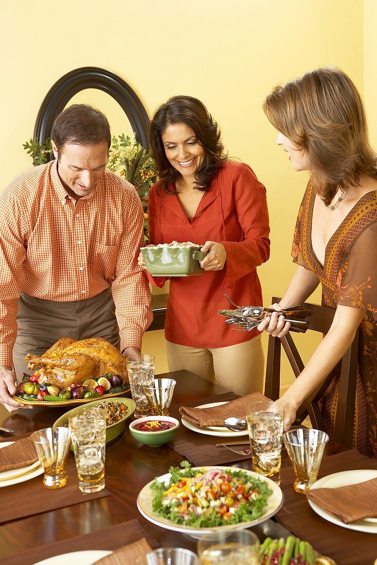 Leute decken Tisch mit Turkey und Beilagen zu Thanksgiving