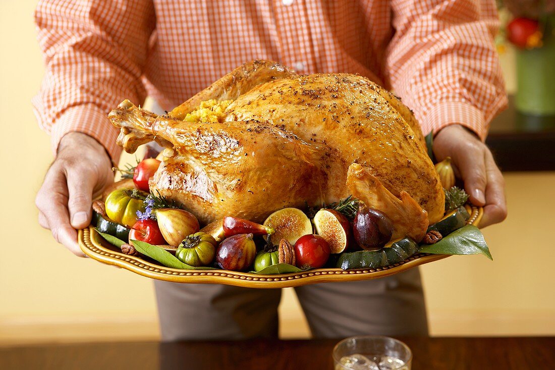 Hände halten Platte mit gebratenem Turkey zu Thanksgiving