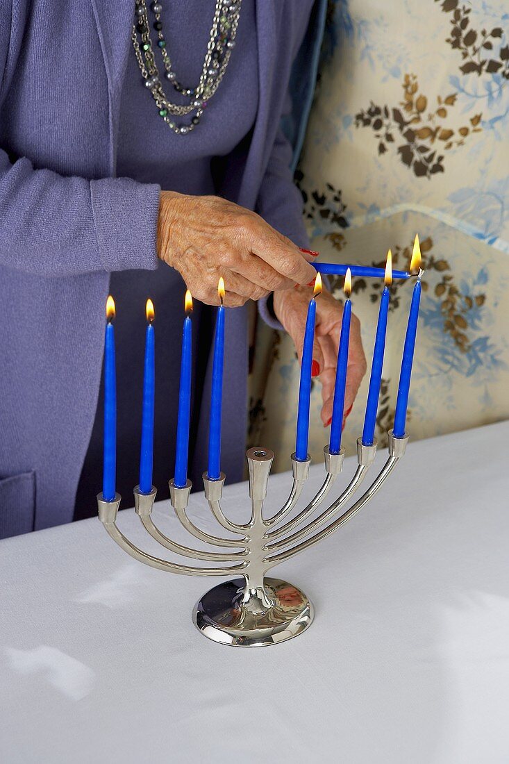 Womans Hand Lighting Manora with Blue Candles