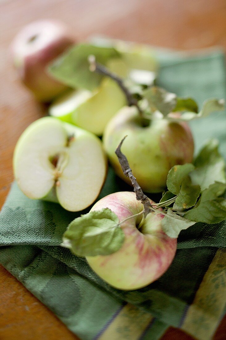 Whole and half apples with leaves on tea towel