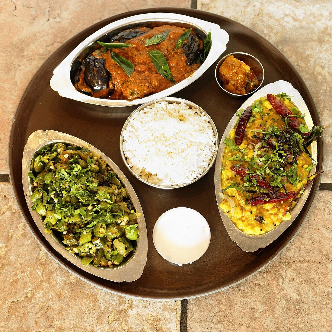 Drei verschiedene Gerichte aus Indien mit Reis auf Tablett