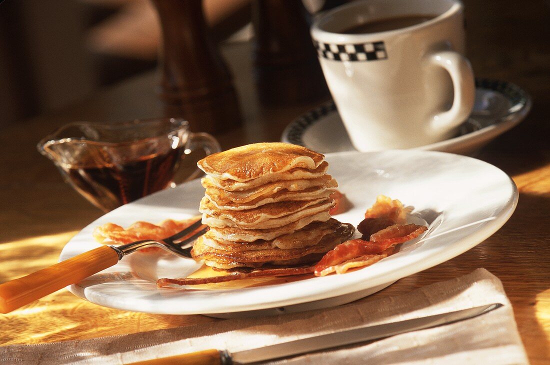 Pancakes mit Speck, Ahornsirup und Tasse Kaffee
