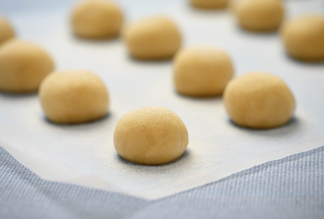 Many Uncooked Balls of Sugar Cookie Dough on Parchment Paper