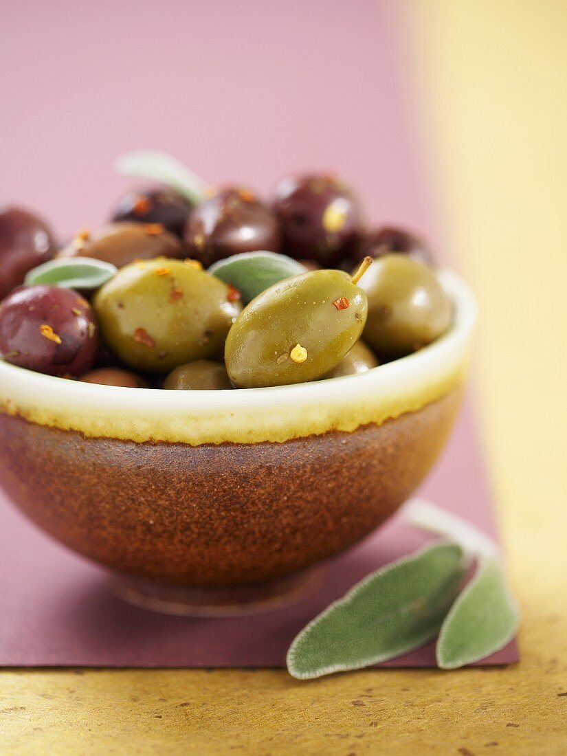 Marinierte Oliven mit Salbei in brauner Schale
