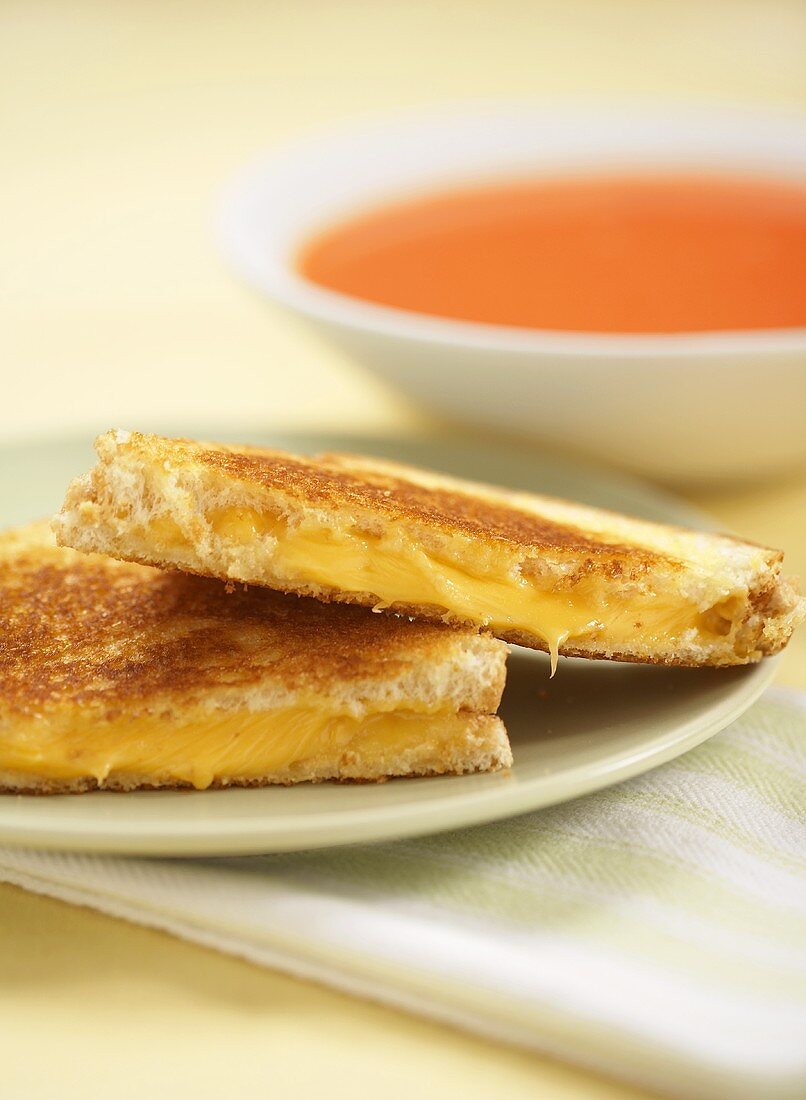 Grilled Cheese Sandwich Cut in Half on a Plate with a Bowl of Soup