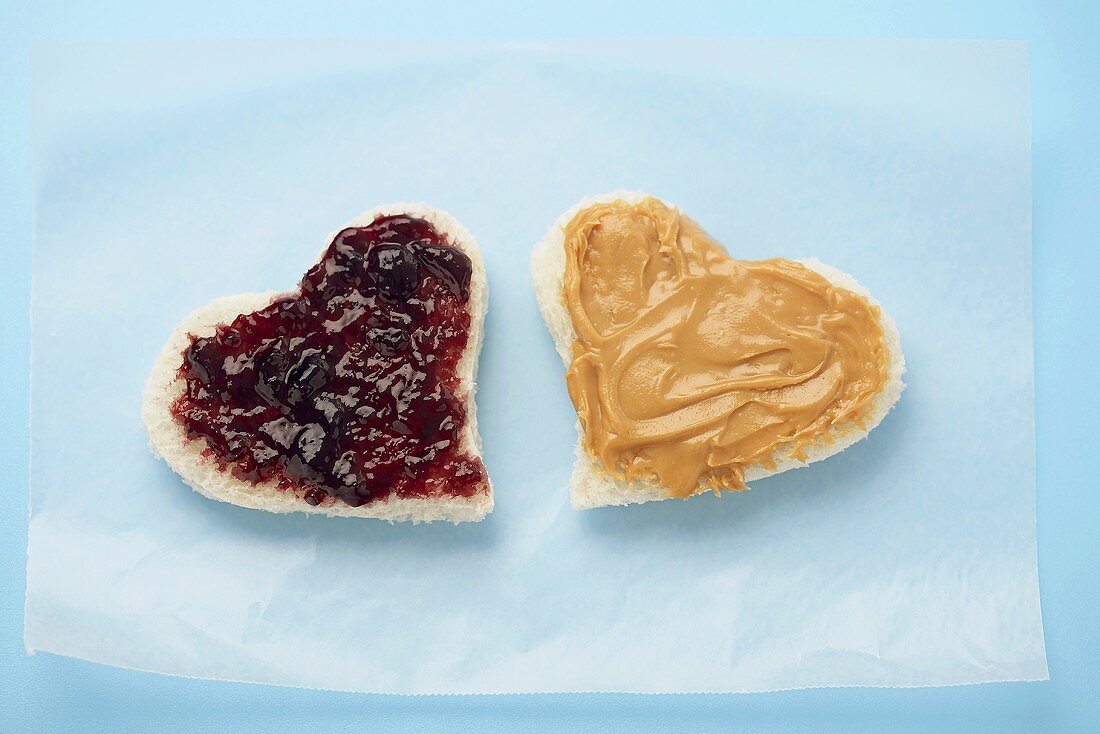 Herzförmige Weissbrotscheiben mit Erdnussbutter und Marmelade