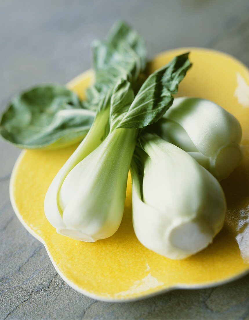 Three Stalks of Baby Bok Choy on a Yellow Plate