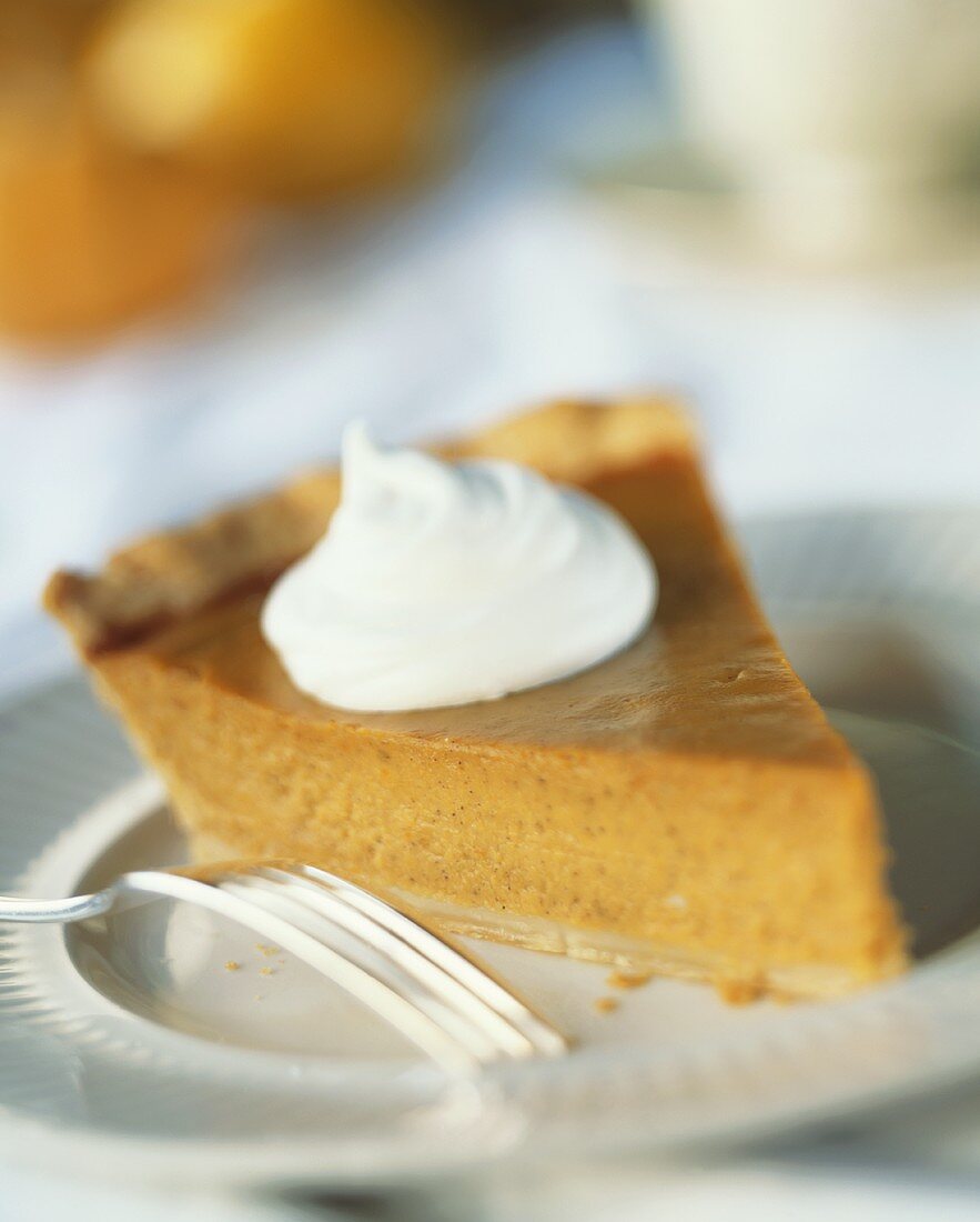 Slice of Pumpkin Pie with a Dollop of Whipped Cream on a Plate; Fork