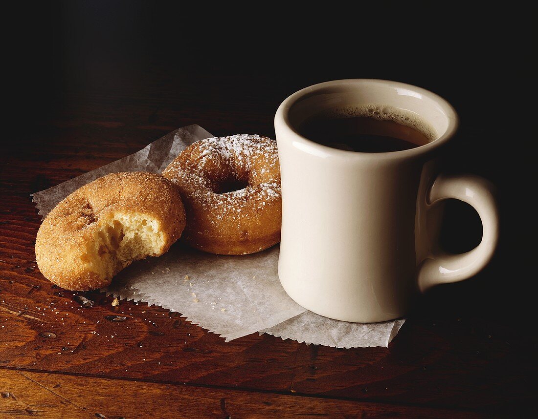 Tasse Kaffee und zwei Donuts (eines angebissen)