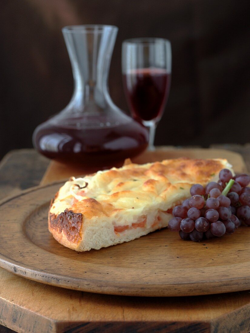 Stück Tomaten-Zwiebel-Focaccia, rote Trauben, Rotwein