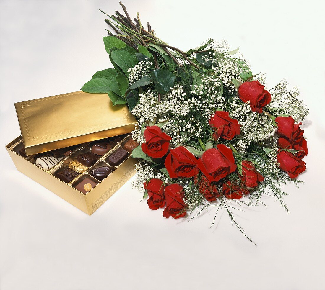 Box of Assorted Chocolates with a Dozen Red Roses on White Background