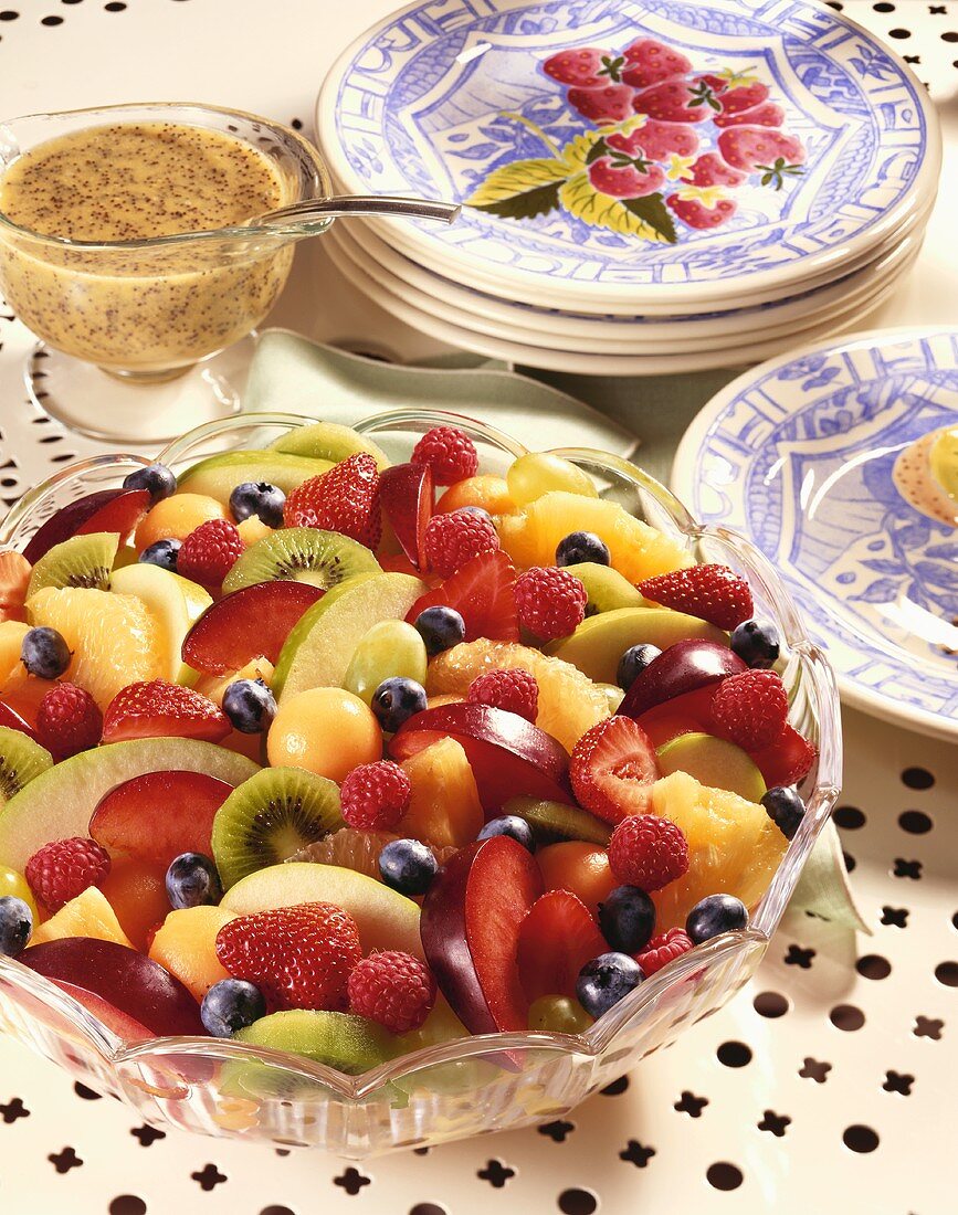 Large Bowl of Fruit Salad with a Small Bowl of Poppy Seed Dressing; Plates