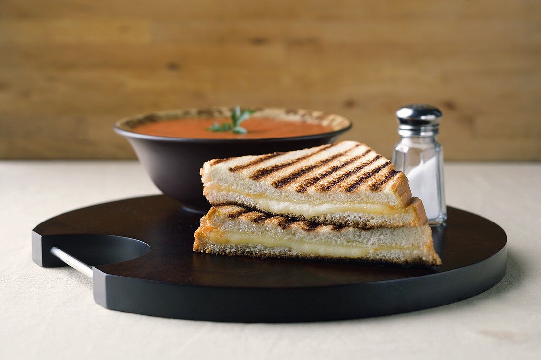 Grilled Cheese Sandwich Cut in Half with a Bowl of Tomato Soup