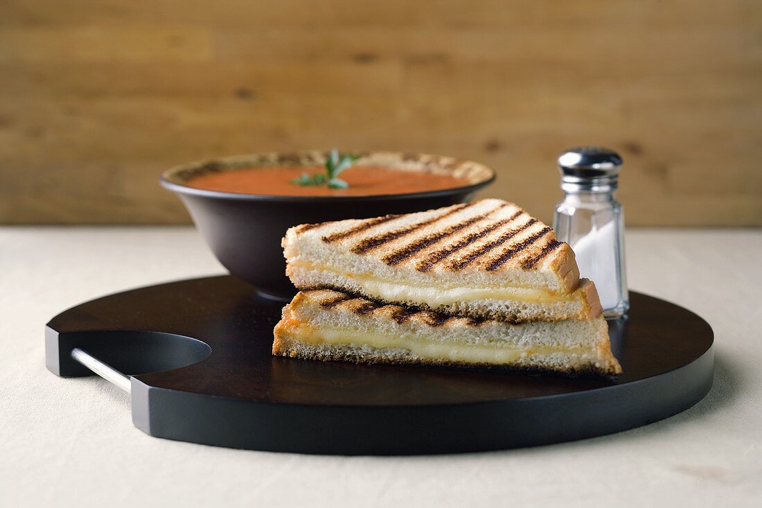 Käsetoasts vor einer Schale Tomatensuppe, Salzstreuer