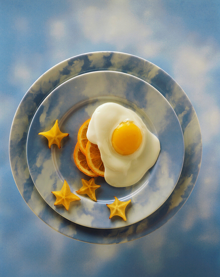 A Fried Egg with Orange Slices and Star Fruit on a Sky Plate and Background