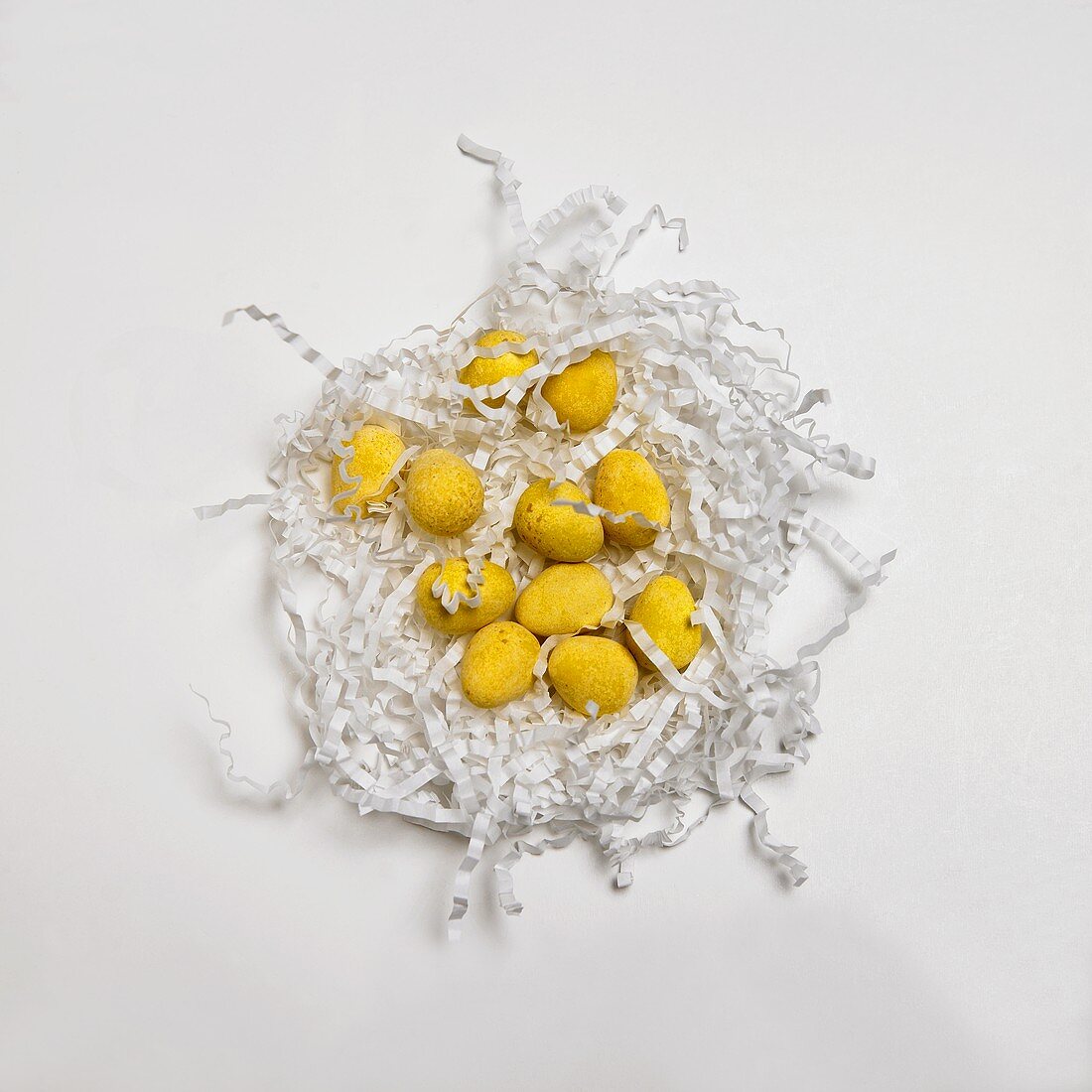 Gelbe Eierbonbons auf weißem Ostergras