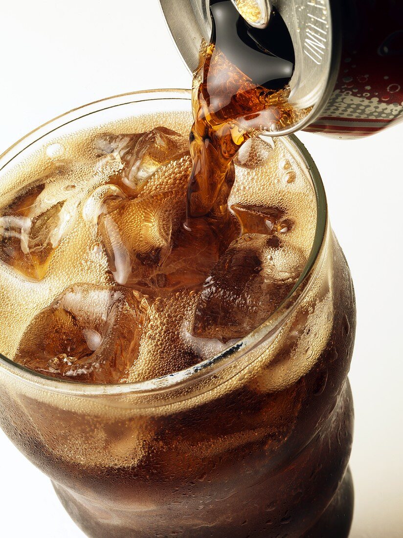 Cola aus Dose in Glas mit Eiswürfeln gießen
