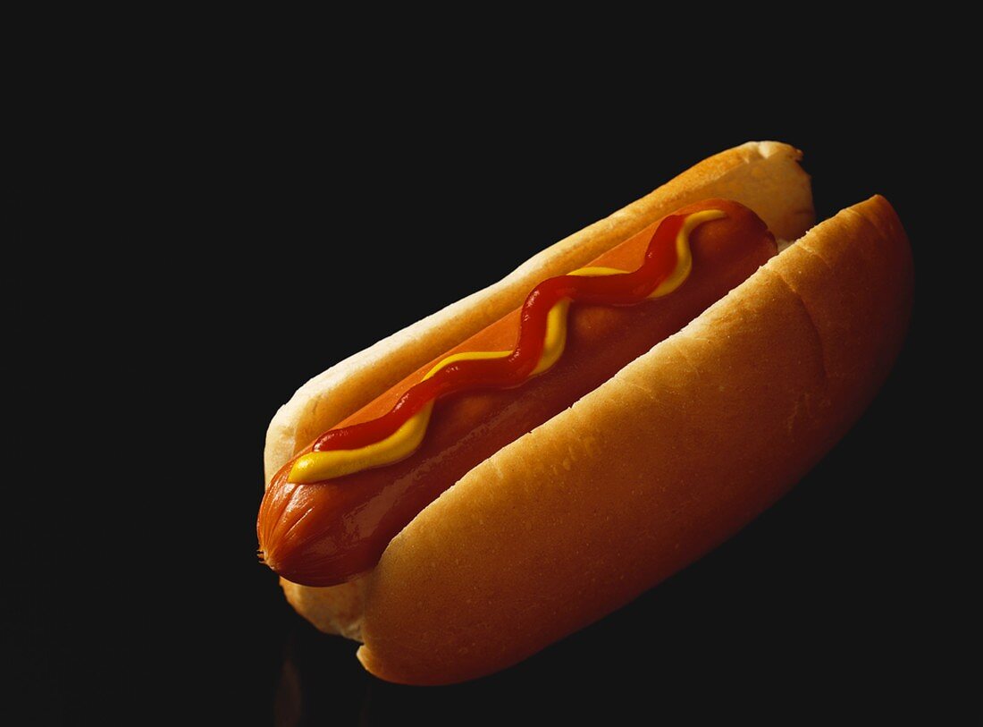 Hotdog mit Ketchup und Mustard auf schwarzem Untergrund