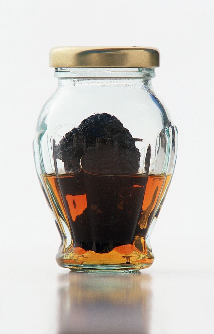 Black Truffle Mushrooms in a Jar on a White Background