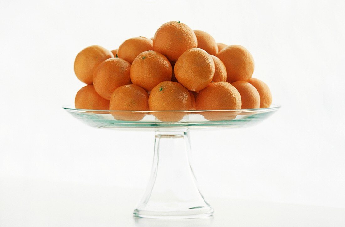 Clementines on a Clear Glass Pedestal Dish, White Background