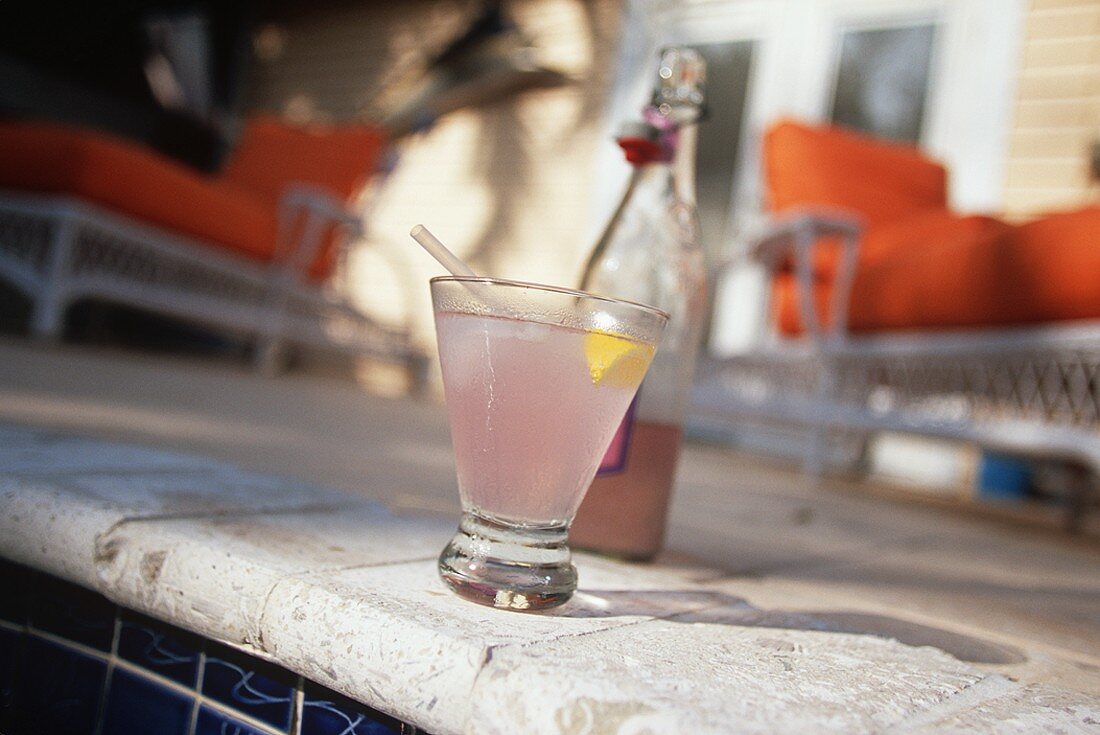 Glass of Pink Lemonade on Edge of Pool