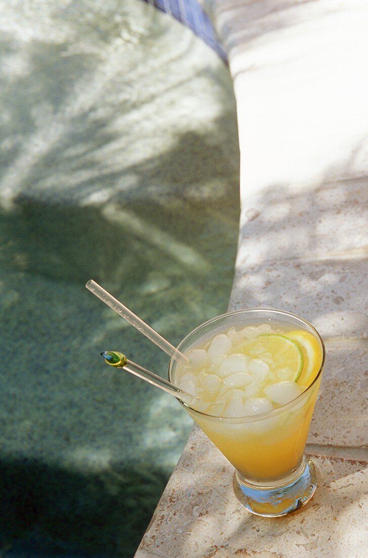 Zitronendrink mit Rum und Eiswürfeln am Rand vom Swimmingpool