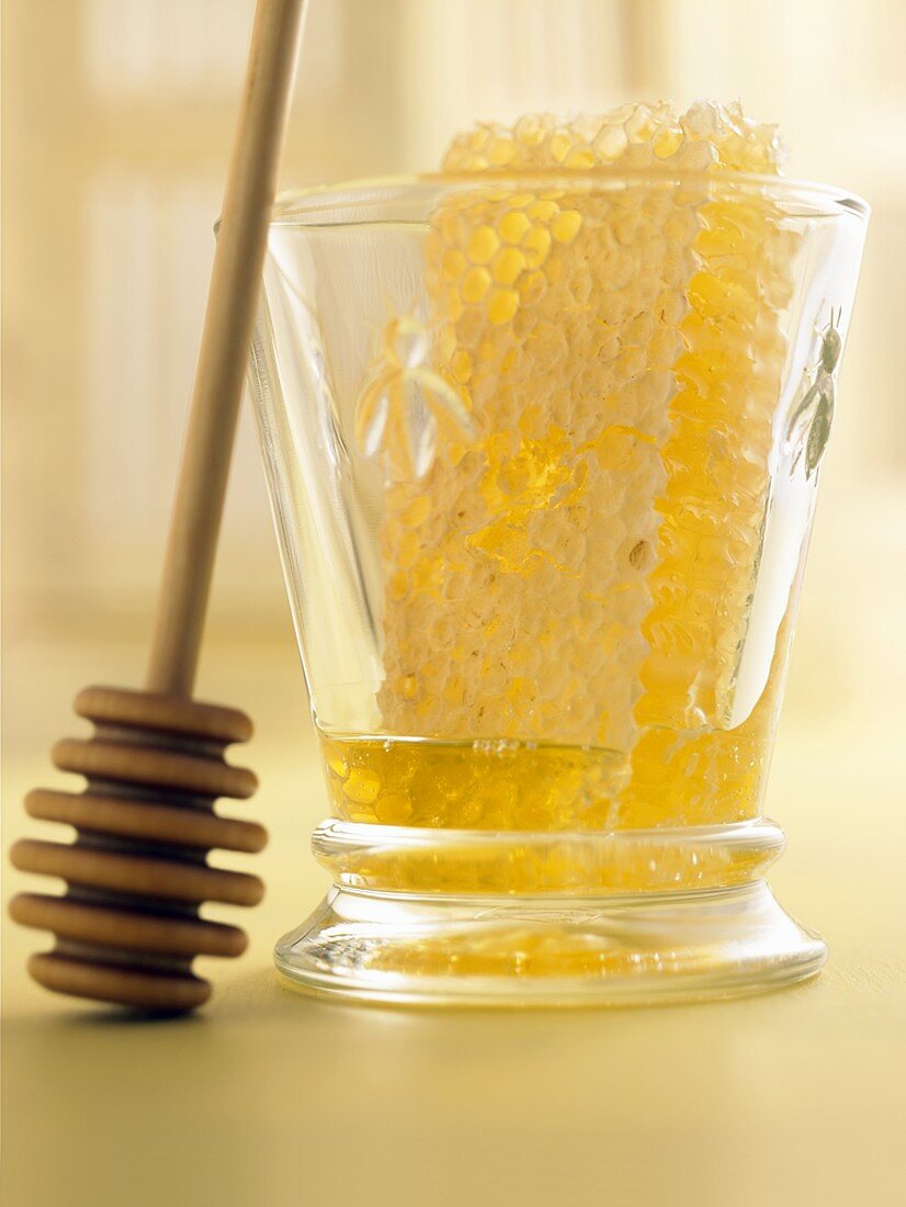 Honig mit Honigwabe im Glas, daneben Honigkamm