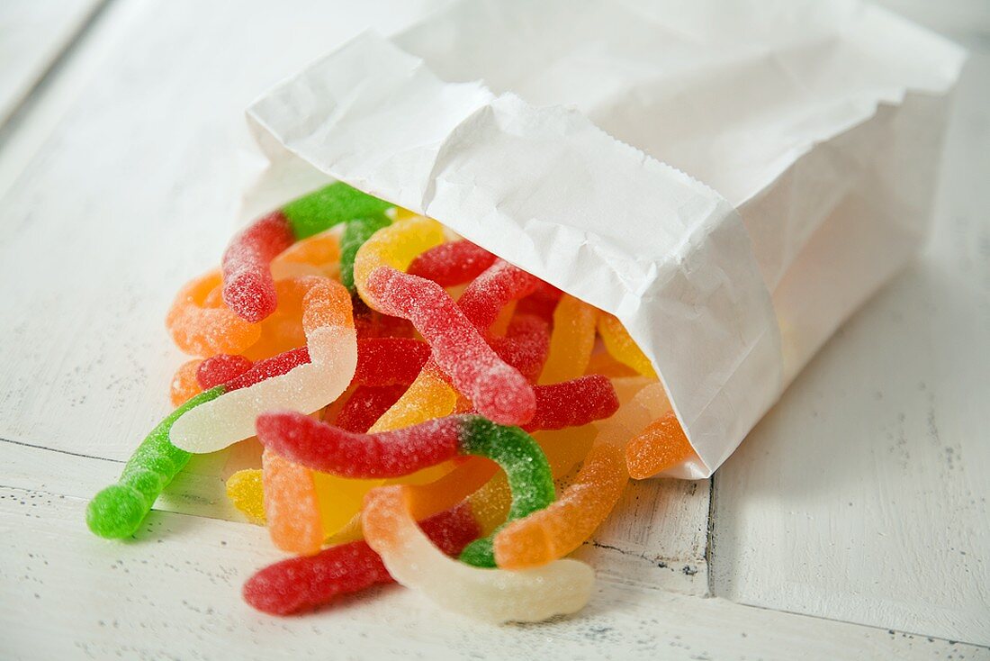 Sweet and Sour Gummy Worms Spilling From a Paper Bag