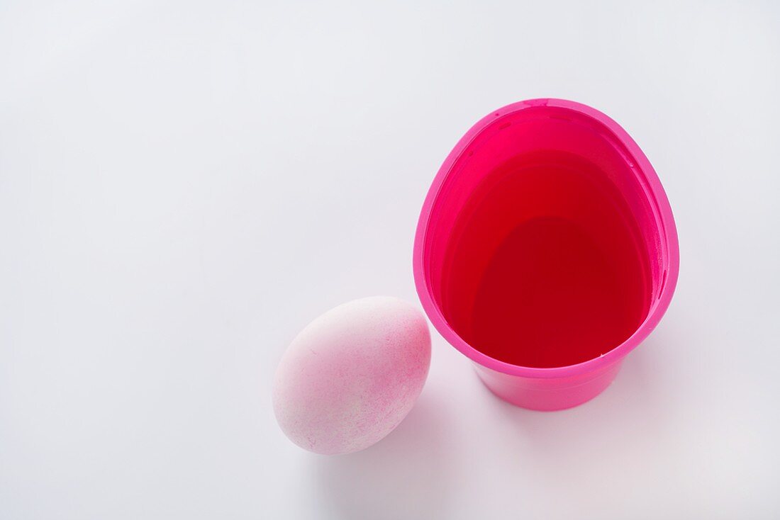 A Colored Egg Next to an Easter Egg Coloring Cup