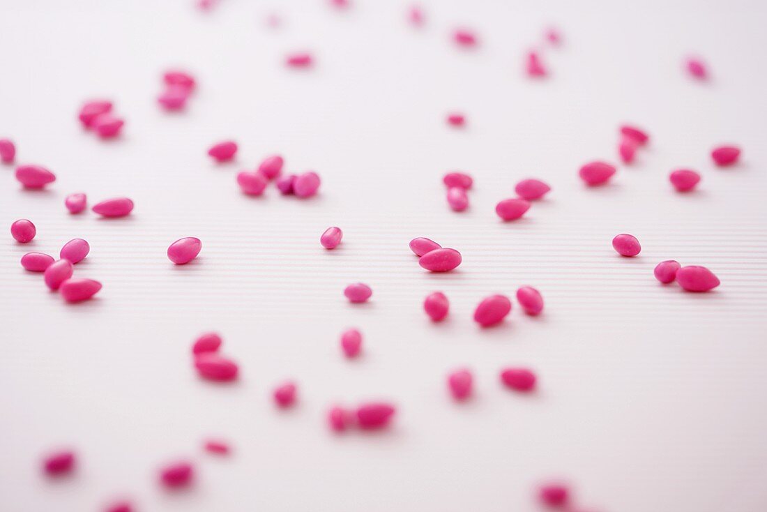 Pink Candy Covered Sunflower Seeds Scattered on a White Background
