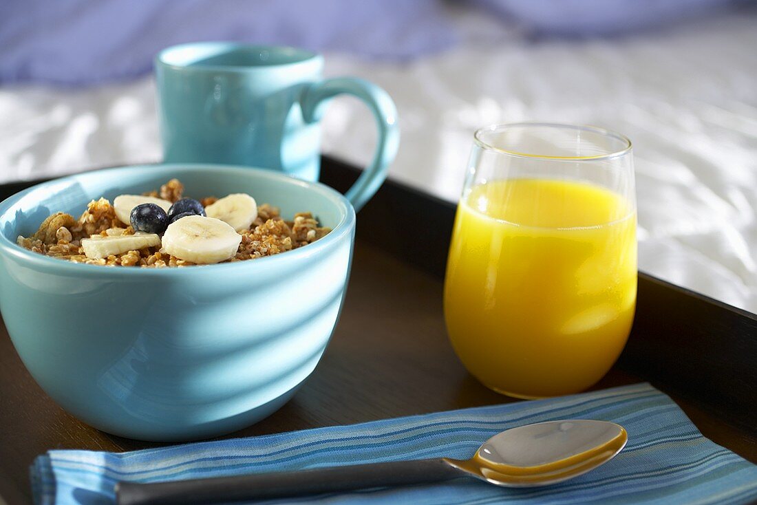 Bowl of Granola Cereal with Juice and Coffee on a Tray in Bed