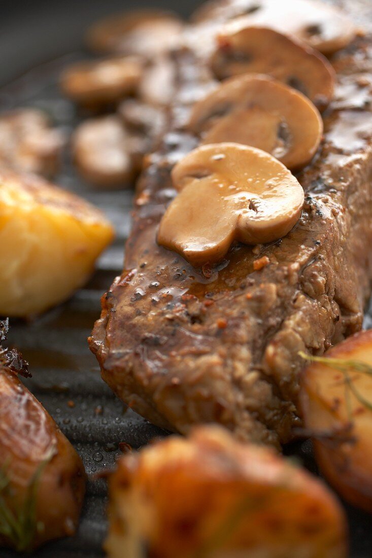 Close Up of Sirloin Steak Topped with Mushrooms on Broiler Pan