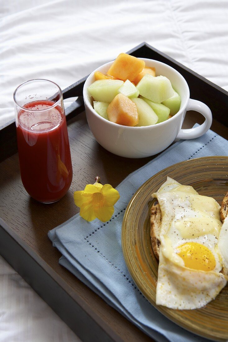 Frühstückstablett mit Melone, Spiegelei und Blutorangensaft