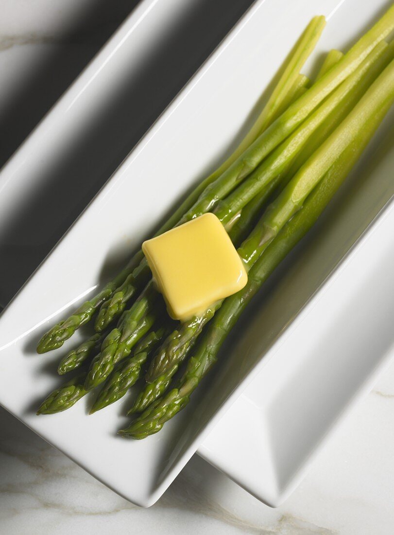 Steamed Organic Asparagus with Butter on a White Serving Dish